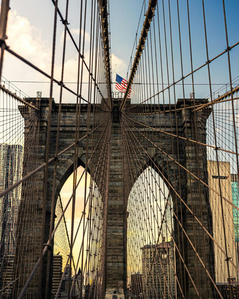 Captivating view of the Brooklyn Bridge with an American flag at sunset.